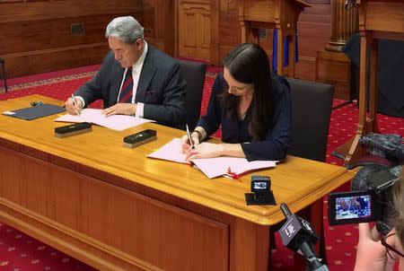 New Zealand Prime Minister-designate Jacinda Ardern signs official documents next to New Zealand First party leader Winston Peters after their meeting in Wellington, New Zealand, October 24, 2017. REUTERS/Nicolaci da Costa