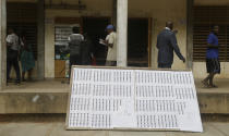 People walk past a board with names of voters as Electoral officials count ballot papers at the end of voting in one of the polling stations in Lome, Togo Saturday, Feb. 22 2020. The West African nation of Togo is voting Saturday in a presidential election that is likely to see the incumbent re-elected for a fourth term despite years of calls by the opposition for new leadership. Photo/ Sunday Alamba)