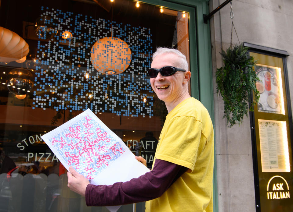 Blind artist Clarke Reynolds with his braille artwork at the ASK Italian in Park Street, central London