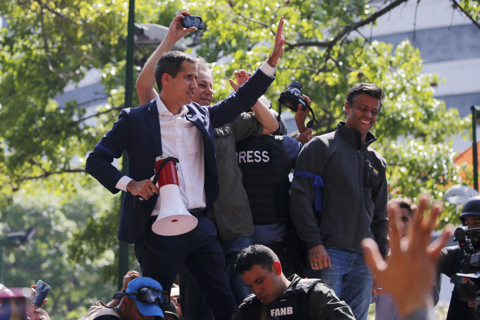 Venezuela's self-proclaimed president Juan Guaido, holding megaphone, and opposition leader Leopoldo Lopez, top right, stand before supporters in Altamira Plaza in Caracas, Venezuela, Tuesday, April 30, 2019. Guaidó and Lopez took to the streets with a small contingent of heavily armed troops early Tuesday in a bold and risky call for the military to rise up and oust President Nicolas Maduro. (AP Photo/Fernando Llano)