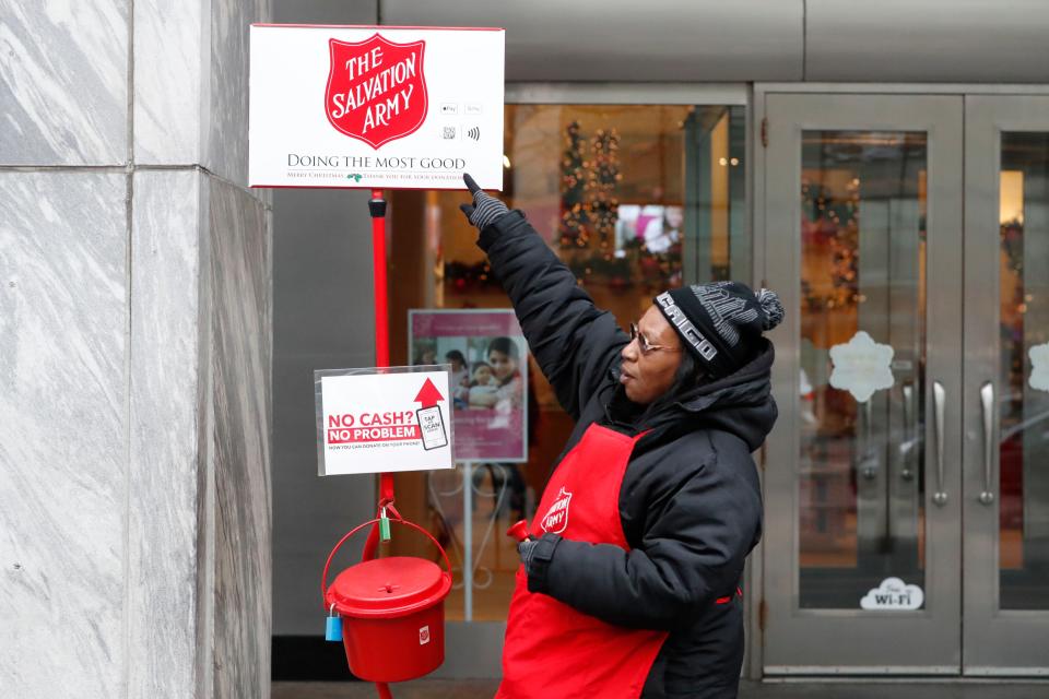 Bell ringer Carolyn Harper points to two ways to donate to the Salvation Army's annual holiday Red Kettle campaign on Chicago's Magnificent Mile on Nov. 15, 2019. Cashless shoppers can donate via their smartphones.