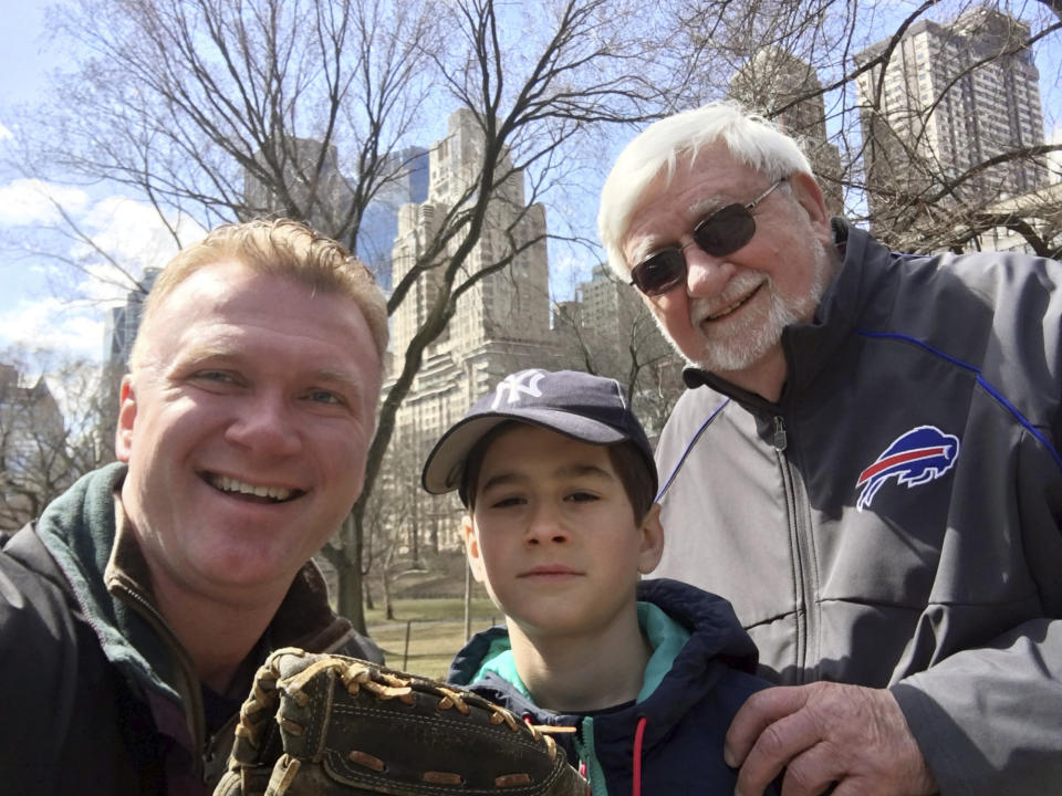 In this March 19, 2019 photo provided by John Pijanowski, Pijanowski, left, poses with his son Jack and father, Don Pijanowski, in New York's Central Park. The elder Pijanowski died of COVID-19, the disease caused by the new coronavirus, in a hospital on April 1, 2020, without having his family at his bedside. (John Pijanowski via AP)