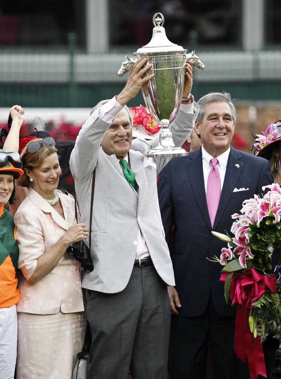 Former Kentucky Governor Brereton C. Jones raised the Oaks trophy with former Louisville Mayor Jerry Abramson , right, and former first lady Libby Jones at his side after winning the 138th running of the Kentucky Oaks at Churchill Downs in Louisville, Ky. on Friday May 4, 2012. Photo by Mark Cornelison | Staff