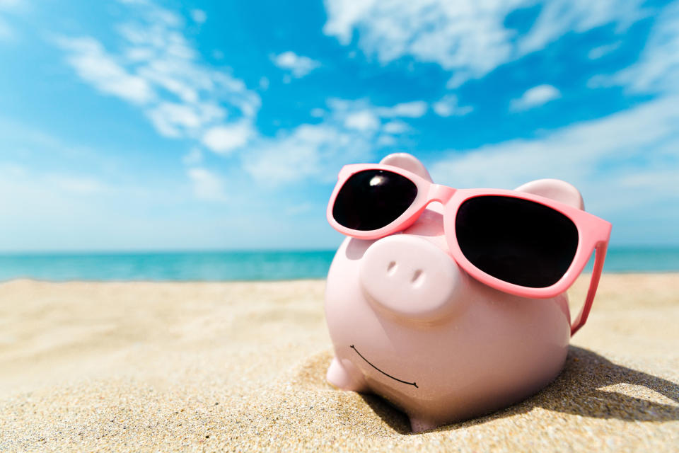 A piggy bank wearing pink sunglasses on a beach