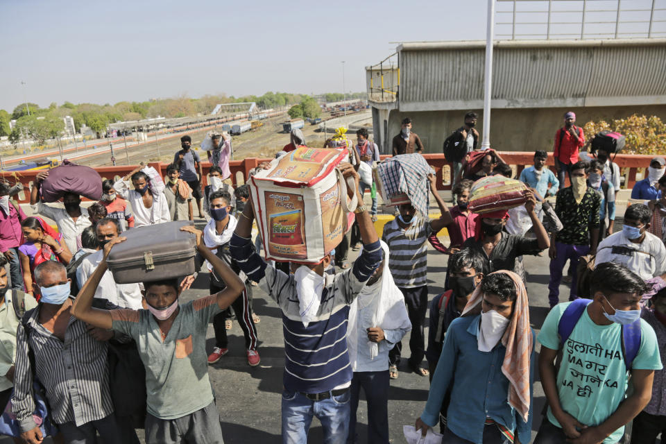 Migrant workers stand on a bridge in search of transportation to take them back to their home states, during a nationwide lockdown to curb the spread of new coronavirus, in Ahmedabad, India, Saturday, May 9, 2020. Locking down the country's 1.3 billion people has slowed down the spread of the virus, but has come at the enormous cost of upending lives and millions of lost jobs. (AP Photo/Ajit Solanki)