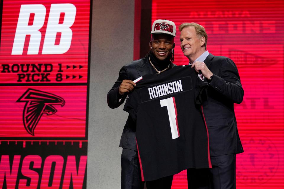 Bijan Robinson shows off an Atlanta Falcons jersey with NFL Commissioner Roger Goodell after being chosen eighth overall Thursday in the NFL draft.