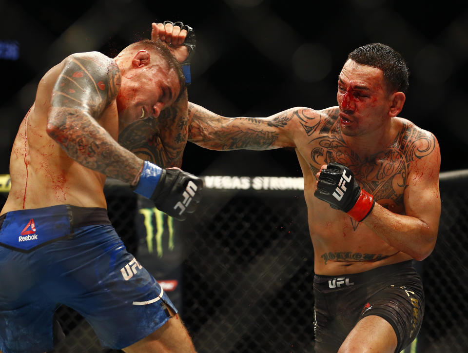 Max Holloway, right, punches Dustin Poirier during an interim lightweight title mixed martial arts bout at UFC 236 in Atlanta, early Sunday, April 14, 2019. (AP Photo/Michael Zarrilli)