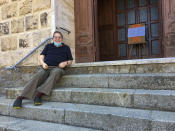 Rev. Lorenzo Pasquotti poses for photos on the steps of his church at the Giglio Island, Italy, Wednesday, June 24, 2020y. Some 50 local mourners filled the pews for that funeral in Saints Lorenzo and Mamiliano Church, including a man from the continent that had COVID-19 infection, recalled the pastor, Rev. Pasquotti. “After the funeral, there were greetings, hugging and kissing,” as always. Then came the procession to the cemetery, where “there were more hugs and kisses.” Yet, “none of us had any sign” of COVID-19 in the days to follow, said Pasquotti. “No one was sick. No symptoms that can make you think you were infected.” (AP Photo/Paolo Santalucia)