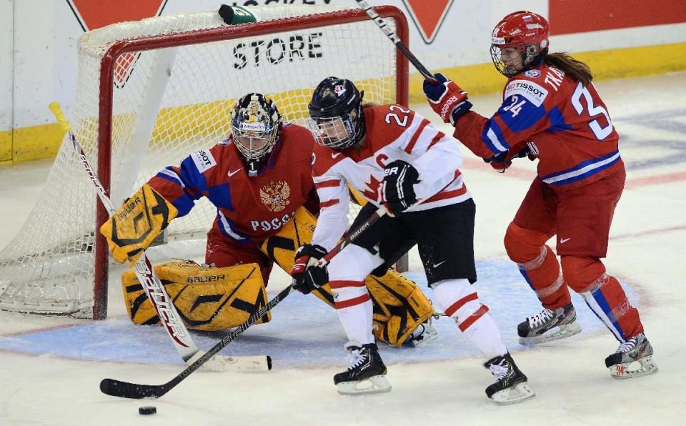 FILE - In this April 8, 2013, file photo, Canada's Hayley Wickenheiser, center, attempts to score on Russia's Anna Prugova as Svetlana Tkachyova defends during the first period of their semifinal game in the women's world hockey championship in Ottawa, Ontario. Since women's ice hockey became an Olympic sport in Nagano in 1998, the Canada and the United States have dominated the podium, winning every gold medal and all but one of the silvers. (AP Photo/The Canadian Press, Sean Kilpatrick, File)