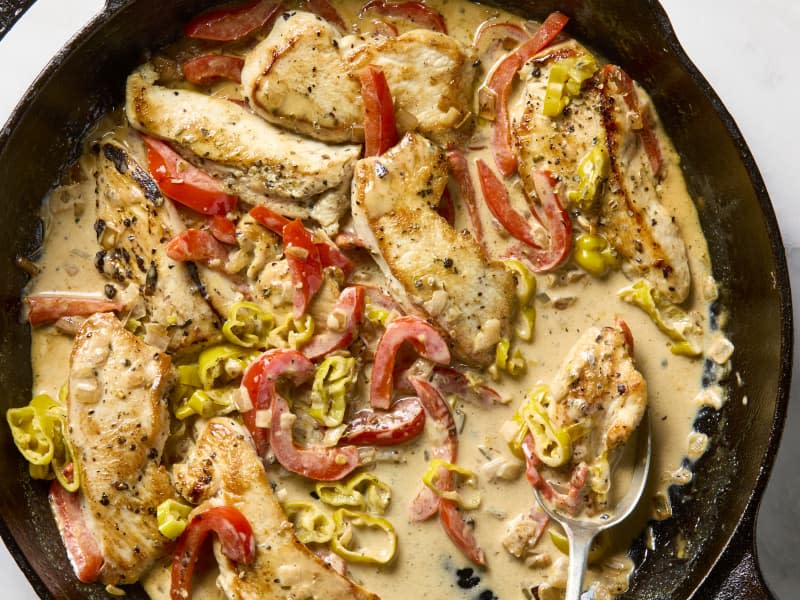 overhead shot of creamy pepperoncini chicken, with red peppers in a pan.