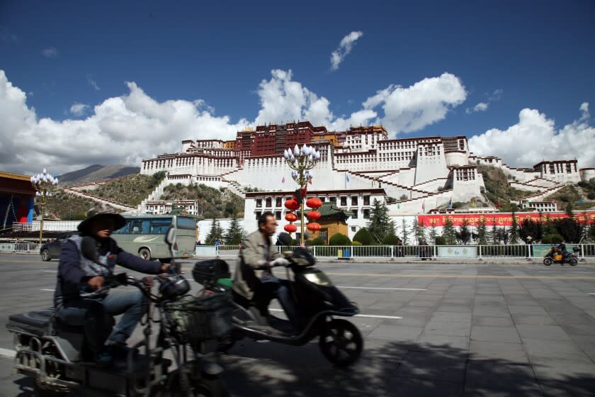 In this Friday, Sept. 18, 2015 photo, people ride scooters past the Potala Palace in Lhasa, capital of the Tibet Autonomous Region of China. (AP Photo/Aritz Parra)