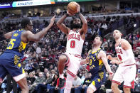 Chicago Bulls guard Coby White (0) drives to the basket against Indiana Pacers forward Jalen Smith, left, and guard T.J. McConnell (9) during the first half of an NBA basketball game in Chicago, Wednesday, March 27, 2024. (AP Photo/Nam Y. Huh)