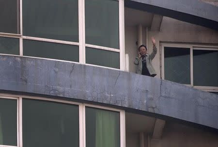 Tibetan writer and activist Tsering Woeser waves from the balcony of her home in Beijing, March 8, 2013. REUTERS/Petar Kujundzic