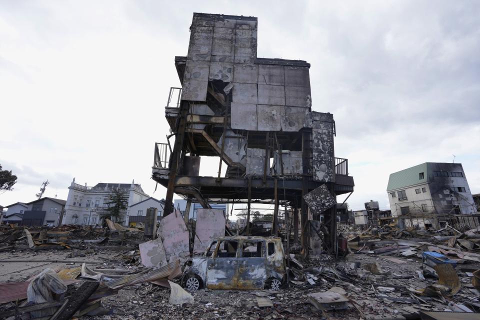 Los restos de un edificio y un auto calcinados luego de un potente sismo, en Wajima, en la península de Noto, el 5 de enero de 2024. (AP Foto/Hiro Komae)