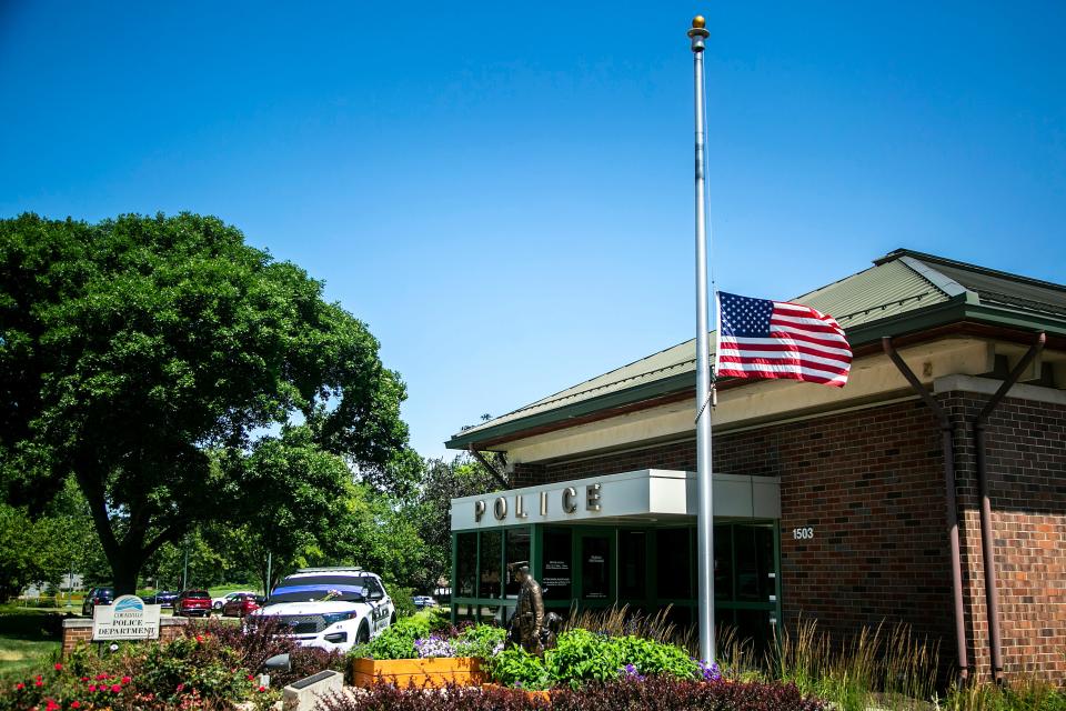 An American flag is shown flying at half-staff next to a police car with a memorial for Coralville police Sgt. John Williams on Tuesday on 5th Street in Coralville. Williams died Sunday of a medical emergency while on duty.