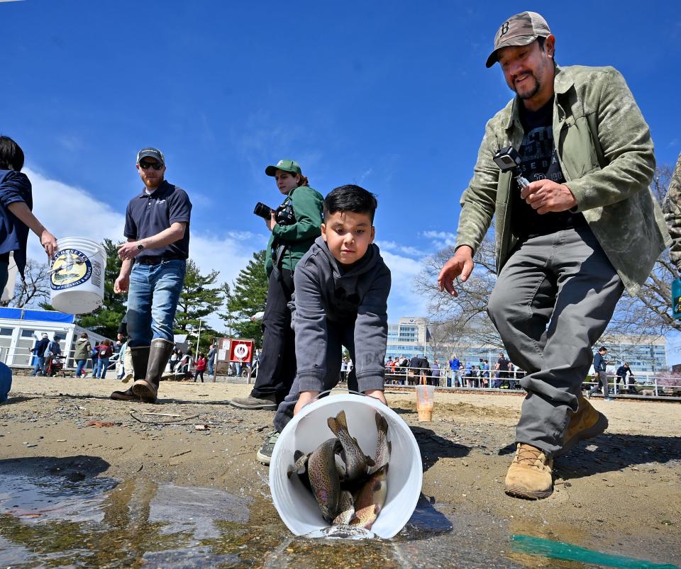 Matthew Molina, 7, of Worcester pours out the trout as his father, Victor, watches.