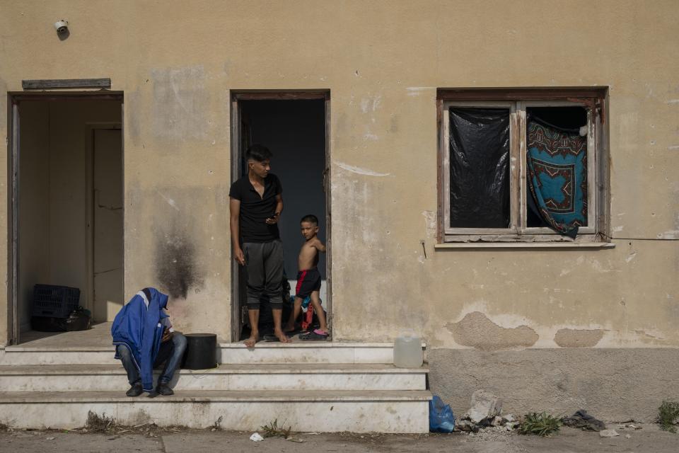 Migrants gather at an abandoned building near Mytilene town, on the northeastern island of Lesbos, Greece, Tuesday, Sept. 15, 2020. Just over 6% of the 12,500 people left homeless last week by the fire that destroyed Greece's biggest camp for refugees and migrants have been rehoused in a new temporary facility under construction on the island of Lesbos. (AP Photo/Petros Giannakouris)