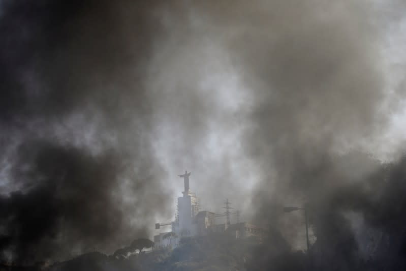 Smoke rises from burning tires as Christ Roi Convent is seen at the background on the highway at Nahr El Kalb