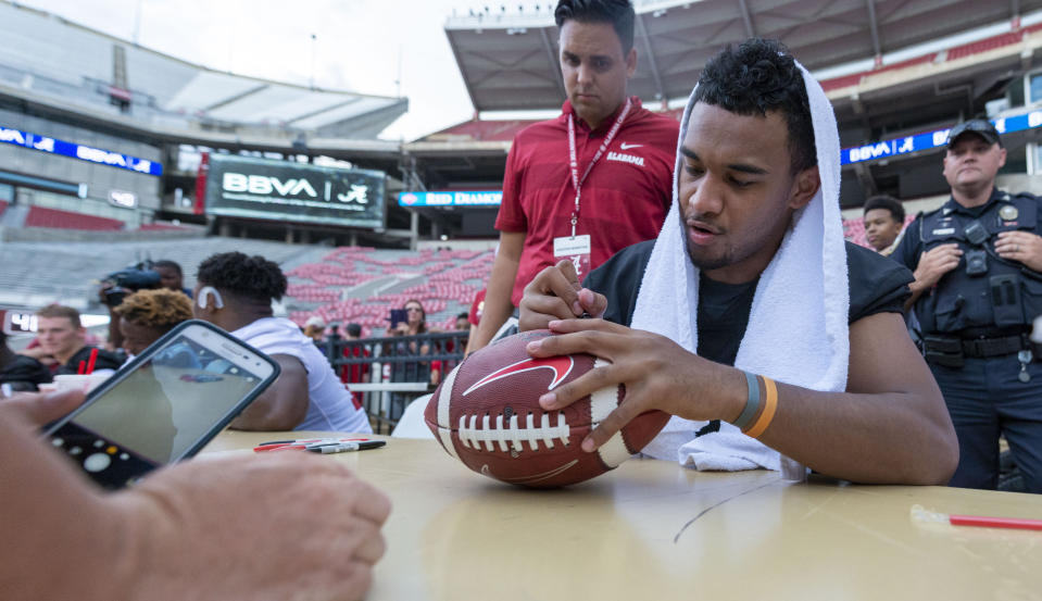 Alabama quarterback Tua Tagovailoa signs a football for a fan during the NCAA college football team's fan-day events following a rain-soaked scrimmage Saturday, Aug. 3, 2019, in Tuscaloosa, Ala. (AP Photo/Vasha Hunt)