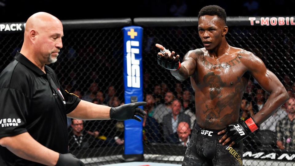 Israel Adesanya reacts and points at his opponent.