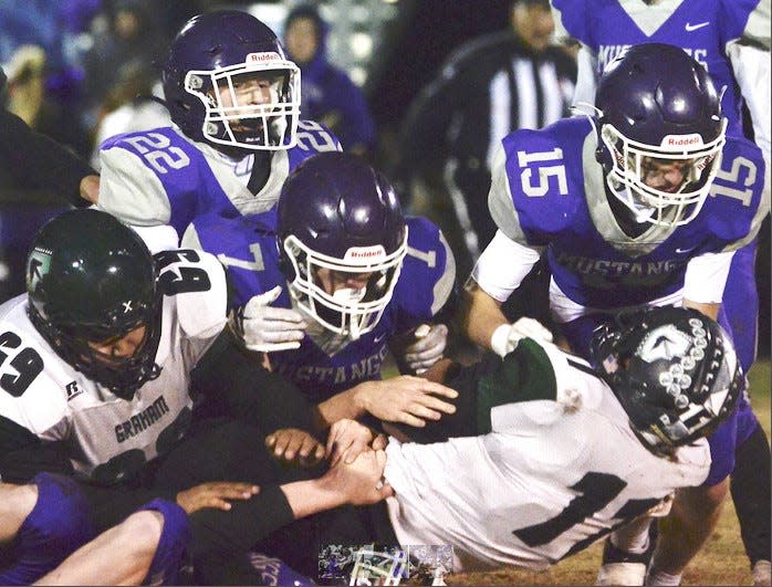 Wesleyan Christian defenders, including Brock Timmons, No. 22, and Carson Tennison, No. 15, bury a Graham-Dustin player during the Class C playoffs Nov. 12, 2022, in Bartlesville. WCS won, 51-28.