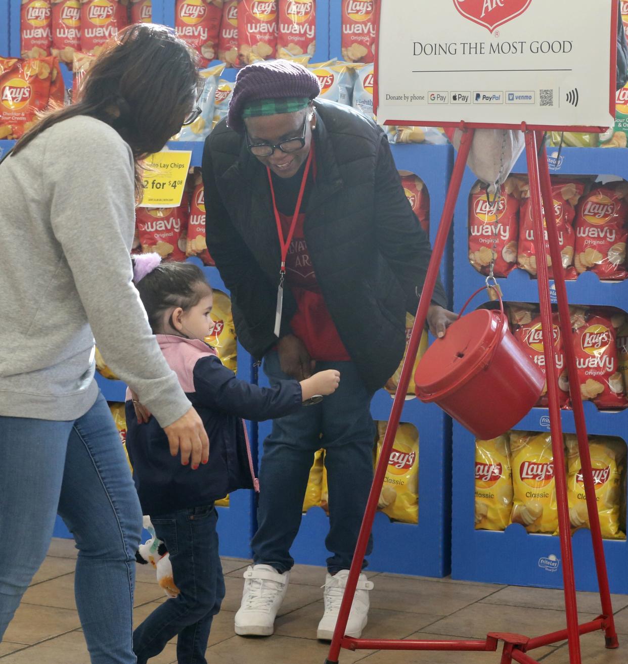 Salvation Army volunteer Diane Hill greets Monroe Noss 3, and her mother Monica as they make a donation Tuesday at the Acme Fresh Market in the Montrose area of Bath Township.