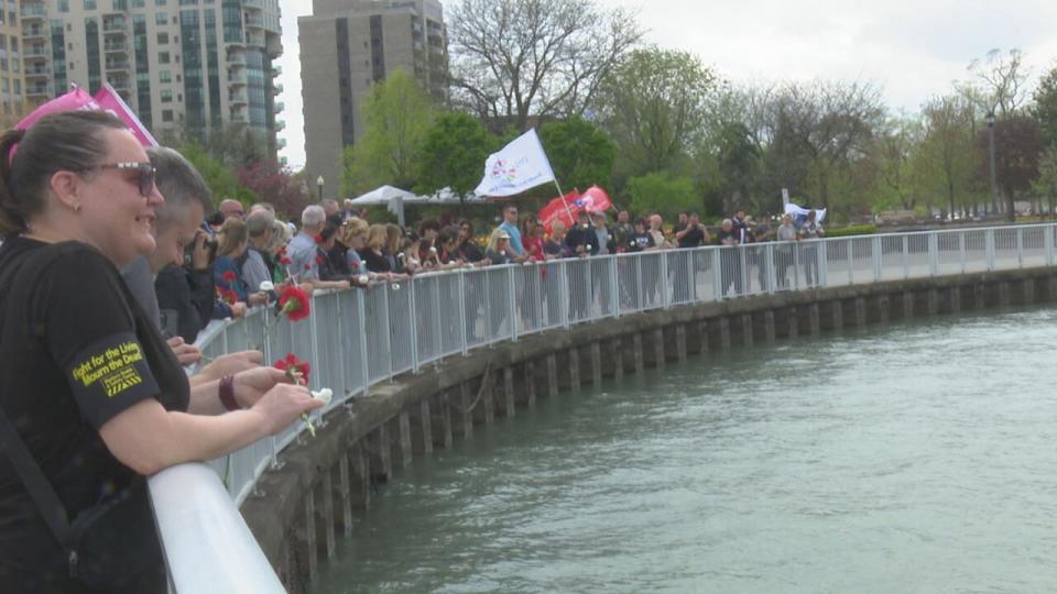 Attendees of the Windsor and District Labour Council's memorial event for fallen workers prepare to throw carnations into the water.