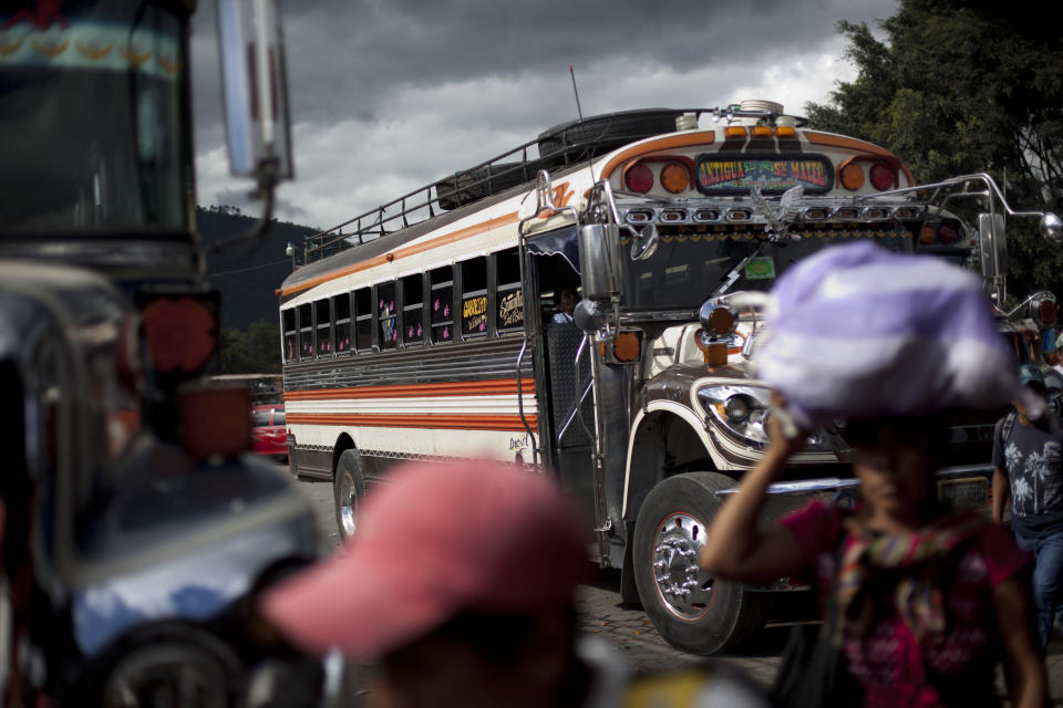 In this Nov. 14, 2013 photo, passengers walk after getting off a bus at the bus terminal in Antigua Guatemala. Bus drivers have been up in arms after one colleague was killed and another wounded in separate attacks because they refused to pay extortion money. The drivers only fully re-established service after the government pledged to crack down on the extortions. (AP Photo/Luis Soto)