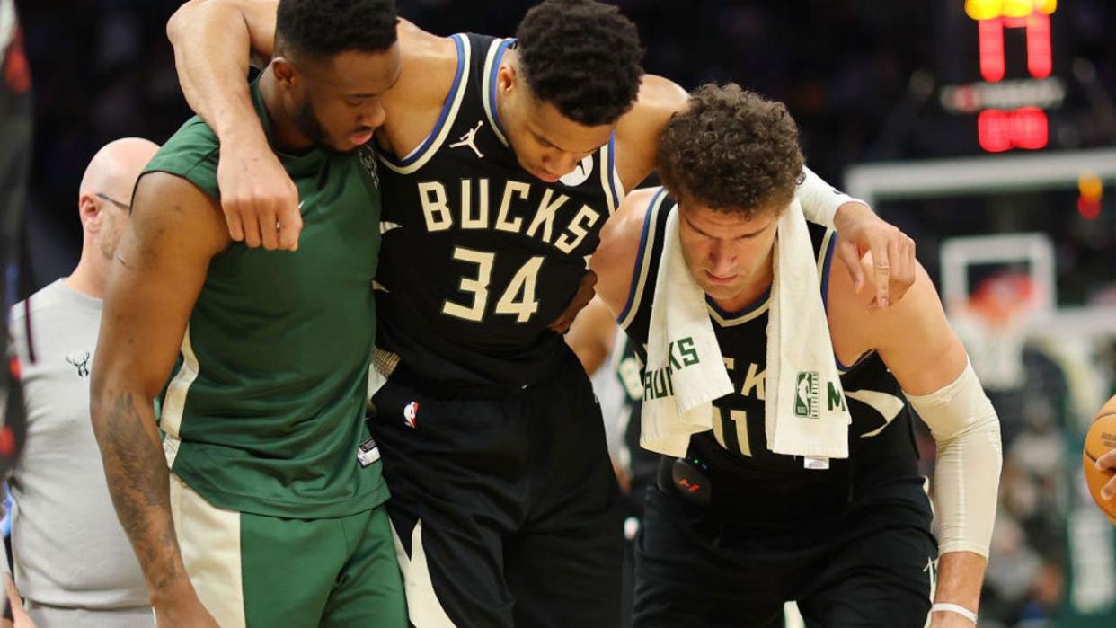 <div>MILWAUKEE, WISCONSIN - APRIL 09: Giannis Antetokounmpo #34 of the Milwaukee Bucks is helped off the court by Thanasis Antetokounmpo #43 and Brook Lopez #11 after suffering an injury during the second half of a game against the Boston Celtics at Fiserv Forum on April 09, 2024 in Milwaukee, Wisconsin. (Photo by Stacy Revere/Getty Images)</div>