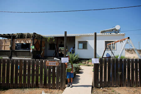 A boy stands at the front gate of a home in the Jewish settler outpost of Amona in the West Bank, during an event organised to show support for Amona, that was built without Israeli state authorisation and which Israel's high court ruled must be evacuated and demolished by the end of the year as it is built on privately-owned Palestinian land, October 20, 2016. REUTERS/Ronen Zvulun