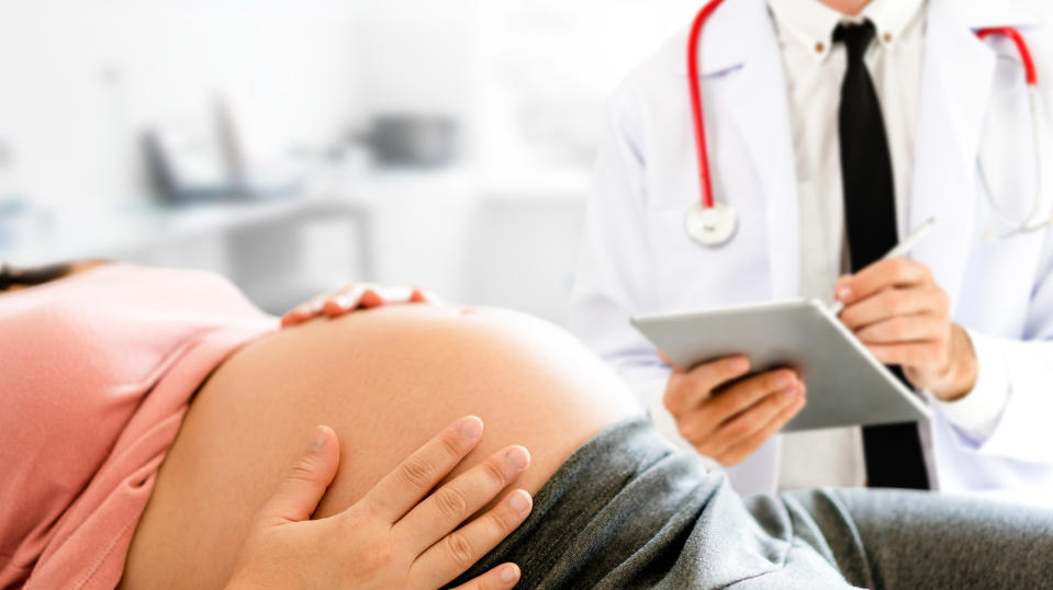 Happy pregnant woman visit gynecologist doctor at hospital or medical clinic for pregnancy consultant. Doctor examine pregnant belly for baby and mother healthcare check up. Gynecology concept.