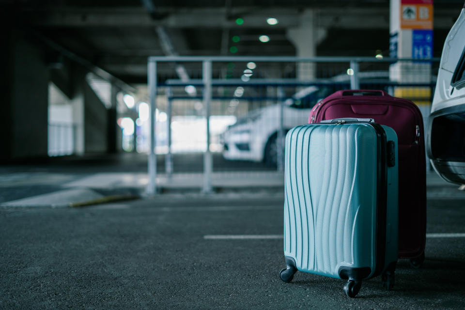 Two suitcases in a parking lot, suggesting travel. No people in the image