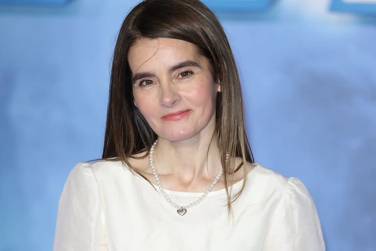 shirley henderson, against a blue cloudy background wearing a white top