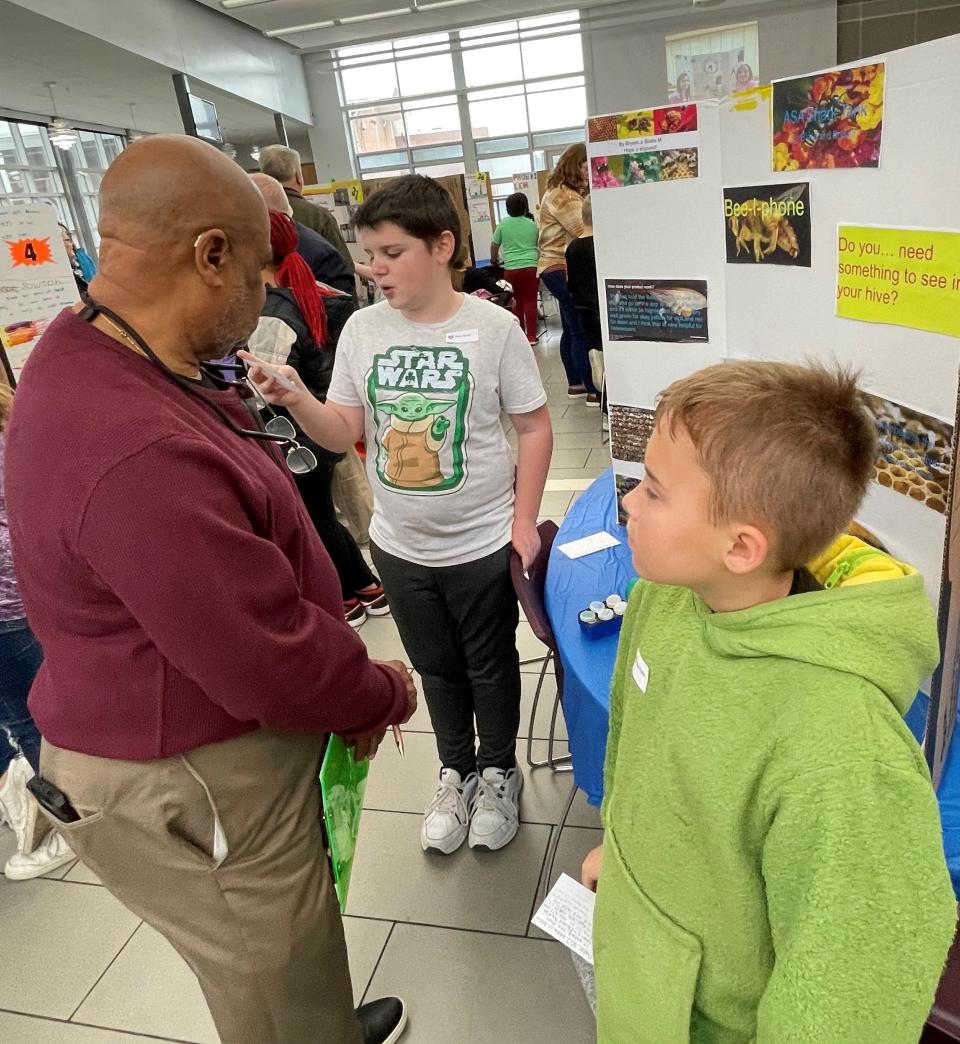 Warren Weber, one of the judges for the Young Entrepreneur Pitch Challenge for Newark elementary students, listens to Blake Moody and Brysen Poulton of Cherry Valley talk about their "Bee-i-phone."