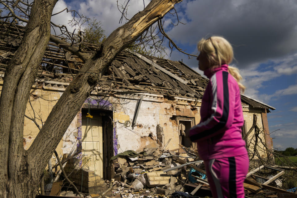 Iryna Martsyniuk, de 50 años, permanece junto a su casa en ruinas tras un bombardeo ruso el jueves 19 de mayo de 2022 en la localidad ucraniana de Velyka Kostromka. Martsyniuk y sus tres hijos pequeños estaban en casa cuando hubo un ataque contra la aldea, ubicada a pocos kilómetros del frente de batalla, pero todos resultaron ilesos. (AP Foto/Francisco Seco)