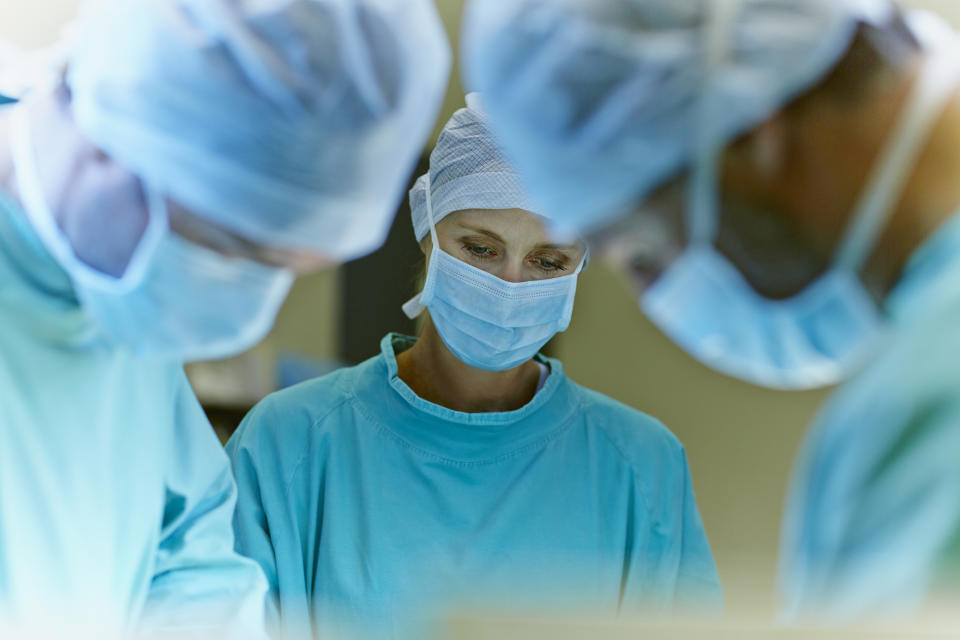 Medical staff in scrubs and surgical masks focused on a procedure