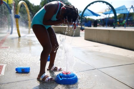A child cools off in a water feature at a park in the Shaw neighbourhood during a heat wave in Washington