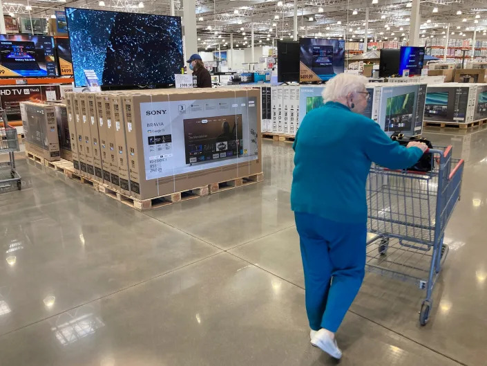 A shopper pushes a cart past flatscreen televisions in a Costco store