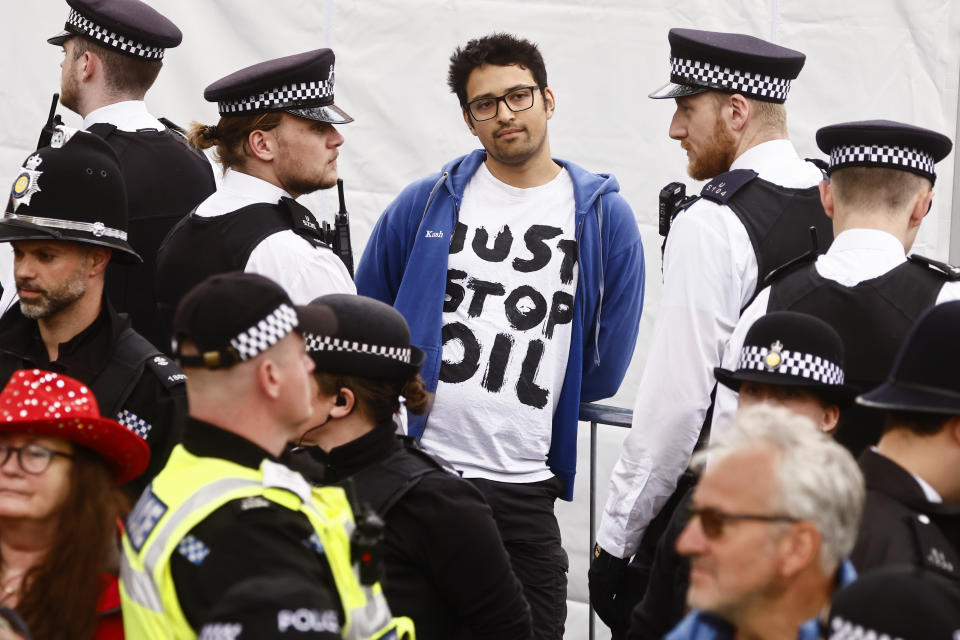 LONDON, ENGLAND - MAY 06: Police officers detain a member of "Just Stop Oil" movement as people gather to watch the procession during the Coronation of King Charles III and Queen Camilla on May 6, 2023 in London, England. The Coronation of Charles III and his wife, Camilla, as King and Queen of the United Kingdom of Great Britain and Northern Ireland, and the other Commonwealth realms takes place at Westminster Abbey today. Charles acceded to the throne on 8 September 2022, upon the death of his mother, Elizabeth II. (Photo by Yara Nardi - WPA Pool/Getty Images)