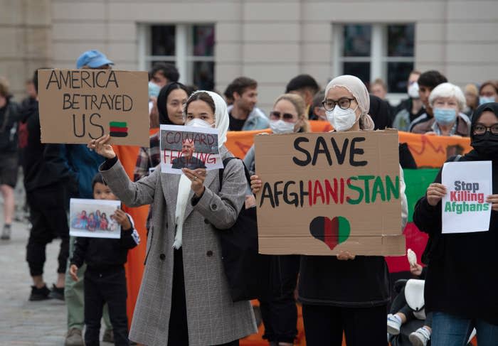 Participants in the rally Humanitarian Airlift Now - Don't Abandon Afghanistan's People stand with placards on the Old Market Square
