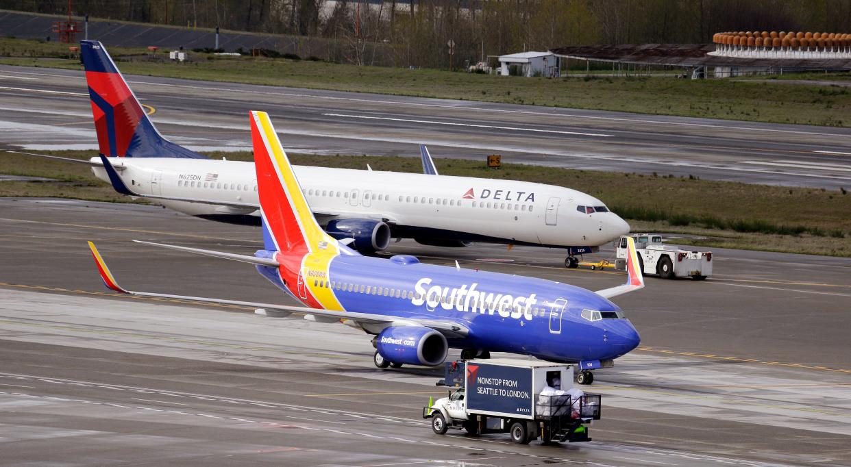 In this photo taken Tuesday, March 24, 2015, a Delta jet is pulled past a Southwest plane at Seattle-Tacoma International Airport in SeaTac, Wash. (AP Photo/Elaine Thompson)