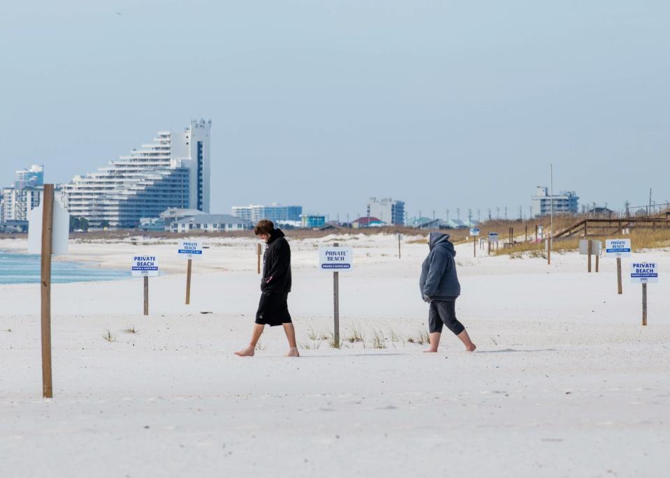 Beach visitors walk past dozens of "private property" and "no trespassing" signs dotting the sandy areas of the beaches on Perdido Key.  A group of local residents wants the county to remove the signs, saying they are an eyesore and unwelcoming to beach visitors.