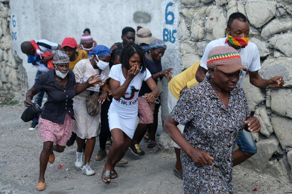 People who were marching to the prime ministers' residence to demand justice for the assassination of Haitian President Jovenel Moise run from tear gas fired by police in Port-au-Prince, Haiti, Wednesday, Oct. 20, 2021.