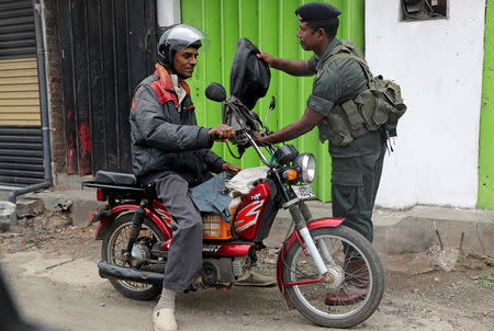 A soldier checks a man on a motorbike outside the Grand Mosque in Negombo, Sri Lanka April 26, 2019. REUTERS/Athit Perawongmetha