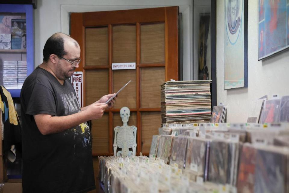 Alex Hernandez, 48, in a Kiss Alive! concert T-shirt and a vintage rock fan, looks for at a record while shopping at Yesterday and Today Records store on west Bird Road at 9274 SW 40th St. in Miami, Florida, Friday, Feb. 2, 2024. He’s been coming to the store for 25 years, he said.
