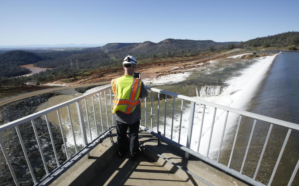 Jason Newton, of the Department of Water Resources, takes a picture of water going over the emergency spillway at Oroville Dam Saturday, Feb. 11, 2017, in Oroville, Calif. Water started flowing over the emergency spillway, at the nation's tallest dam, for the first time Saturday morning after erosion damaged the Northern California dam's main spillway.(AP Photo/Rich Pedroncelli)