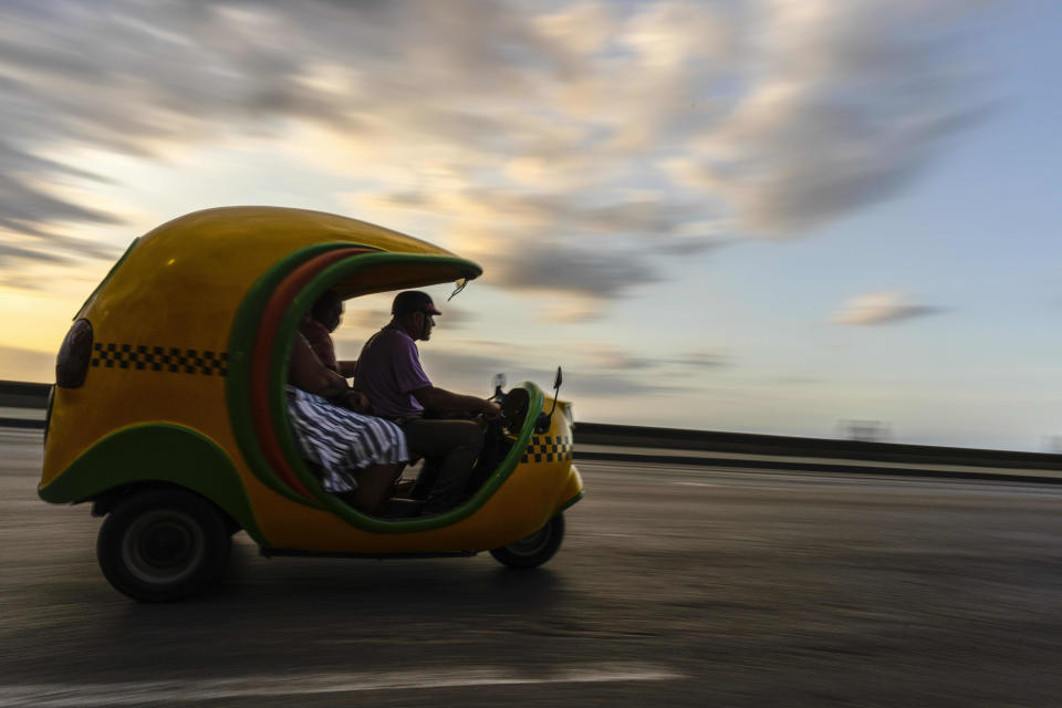 La gente viaja en un taxi Coco que normalmente se usa para el turismo en La Habana, Cuba, el jueves 6 de abril de 2023. (AP Foto/Ramón Espinosa)