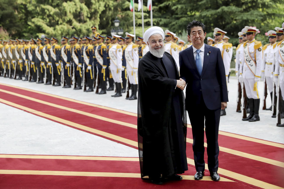 Japanese Prime Minister Shinzo Abe, right, shakes hands for the cameras with Iranian President Hassan Rouhani, during the official arrival ceremony, at the Saadabad Palace in Tehran, Iran, Wednesday, June 12, 2019. The Japanese leader is in Tehran on a mission to calm tensions between the U.S. and Iran. (AP Photo/Ebrahim Noroozi)