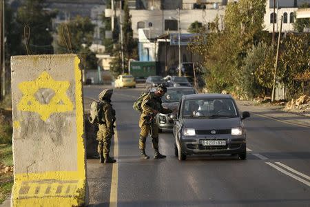 Israeli soldiers check Palestinian cars at a checkpoint at the entrance to the village of Halhul near the West Bank city of Hebron December 1, 2015. REUTERS/Baz Ratner