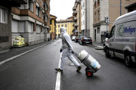 A staffer delivers a medical oxygen tank to coronavirus patients who are being treated at home, in Bergamo, one of the areas worst affected by the virus, Northern Italy, Tuesday, March 31, 2020. The new coronavirus causes mild or moderate symptoms for most people, but for some, especially older adults and people with existing health problems, it can cause more severe illness or death. (Claudio Furlan/LaPresse via AP)